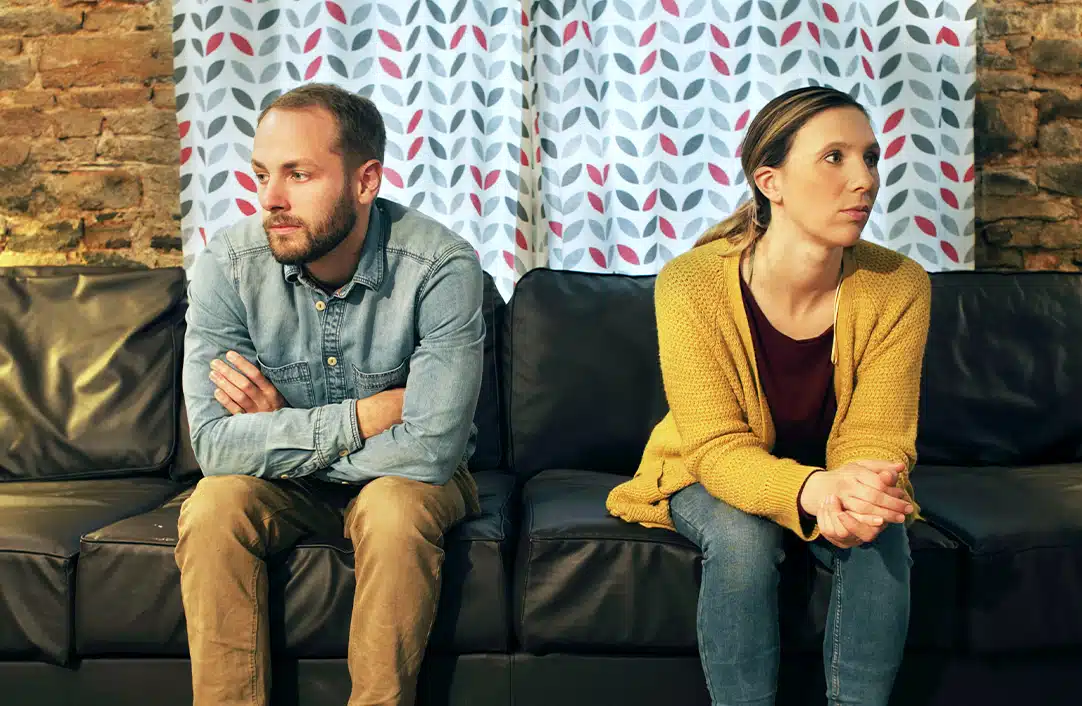 Man and women sitting on couch facing away from each other